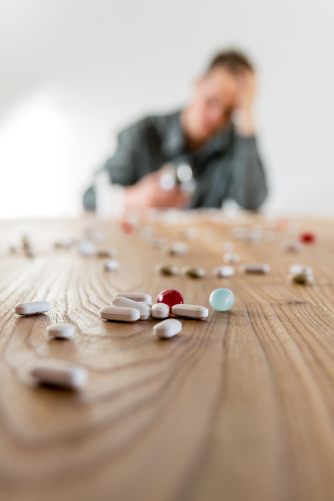 man looking pained with pills
