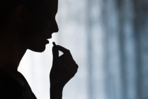 Silhouetted woman taking prescription pill